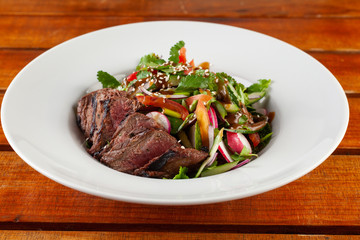 Close-up salad with grilled pork steak on a white plate
