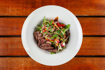 Salad with sliced medium-rare steak on a rustic table