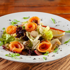 Fresh trout salad with greens and herbs on a white plate