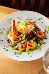 Fresh trout salad with greens and herbs on a white plate