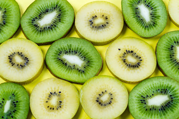 horizontal view of slices of golden yellow and green kiwi fruit on a bright high contrast yellow background