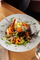 Healthy salmon salad with female hands and flatware