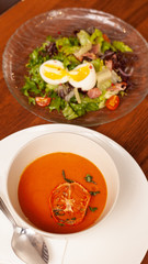 Cosy homemade lunch with spicy tomato soup and cobb salad with bacon and eggs