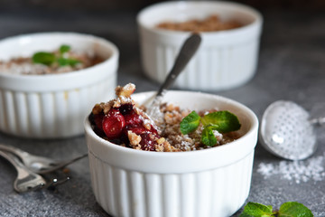 Cherry crumble with nuts and mint on a concrete background.