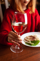 Woman prositting with a glass of white wine during a fancy dinner in a restaurant