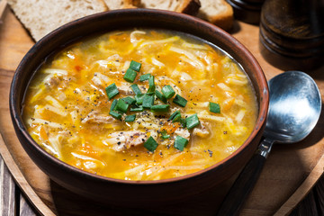 chicken soup with egg noodles on wooden background, closeup