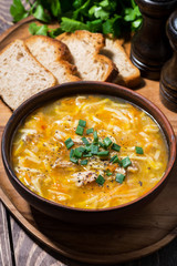 chicken soup with egg noodles on wooden background, vertical closeup