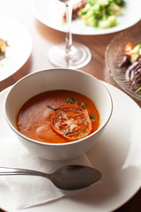 Close up of cold spanish gazpacho decorated with sun dried tomato in a white bowl