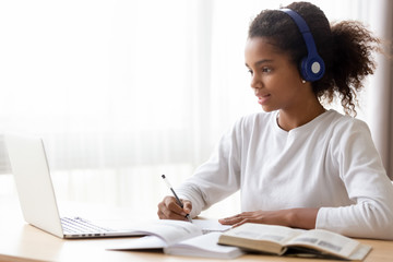 African American teen girl wearing headphones learning language online - Powered by Adobe