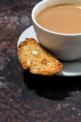 cup of coffee with milk and Italian cookies cantucci on dark background, vertical