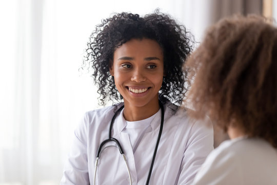 Close up smiling African American pediatrician doctor listening to patient