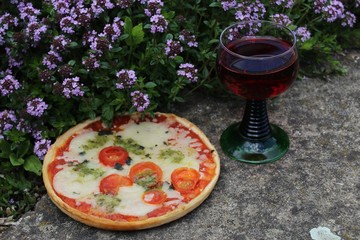 Pizza und Rotwein am blühenden Thymian