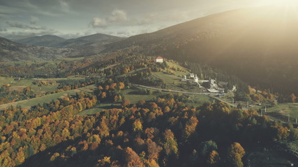 Autumn Forest Mountain Slope Village Aerial View. Panoramic Scenery Hill Meadow Landscape Sight. Wild Nature. Highland Scene of Building Clean Environment. Travel Concept Drone Flight