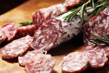thinly sliced salami sausages on a wooden texture on the background.