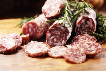 thinly sliced salami sausages on a wooden texture on the background.