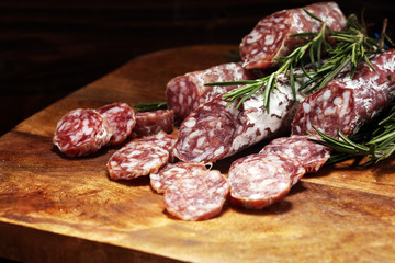 thinly sliced salami sausages on a wooden texture on the background.