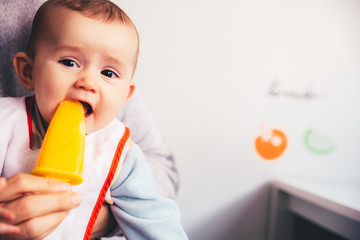 Baby savoring an orange ice cream.