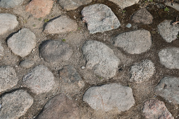 Rough stone pathway in the park. Old pavement made with various stones and pebbles. Grunge stone background. Natural gravel backdrop.