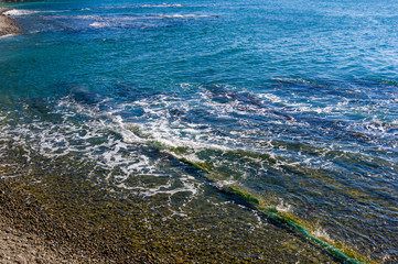 sea landscape is a pebbly beach with waves in white foam