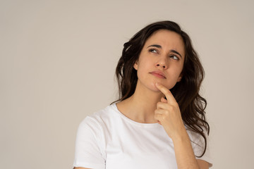Portrait of young attractive woman with thoughtful expression thinking
