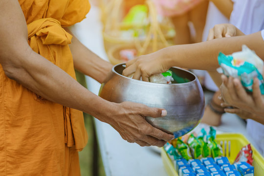 Teachers and students together make merit to give food offerings to a Buddhist monk on important religious days at school.