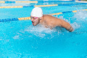 Fototapeta na wymiar Swimmer in underwater glasses and a swimming cap swims in the pool brace