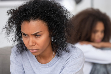 Upset angry African American mother ignoring daughter after quarrel