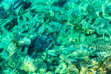 Transparent turquoise sea water with sun glare, background.