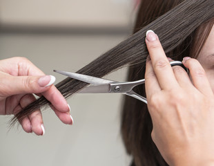 Haircutting process in the hairdresser. woman in the salon smoothes her hair. Hands with scissors. Stock photos for design