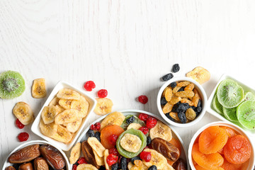 Bowls of different dried fruits on wooden background, top view with space for text. Healthy...