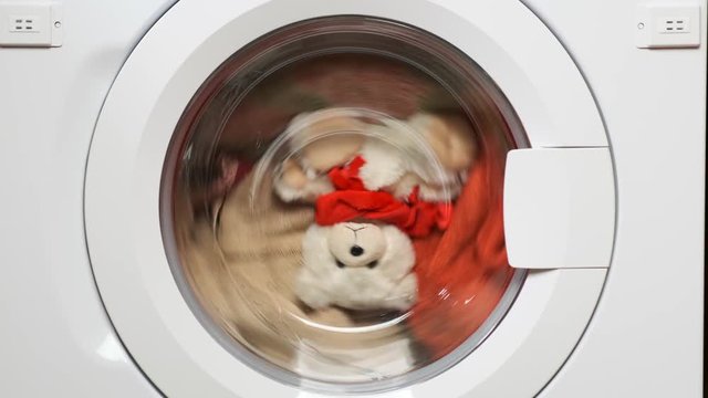 Teddy bear washes in the washing machine. Closeup.