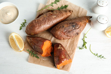 Flat lay composition with baked sweet potatoes on white table