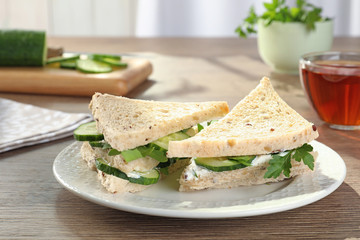 Plate with traditional English cucumber sandwiches on table