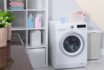 Modern washing machine in laundry room interior