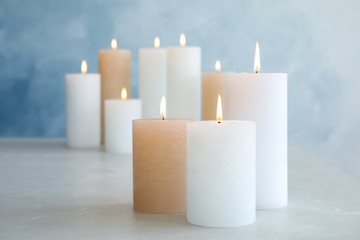 Fototapeta na wymiar Burning candles on table against color background. Space for text