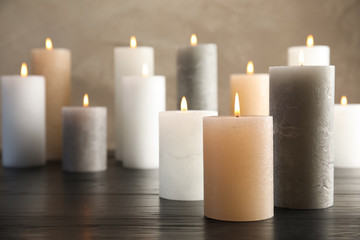 Fototapeta na wymiar Burning candles on table against color background. Space for text