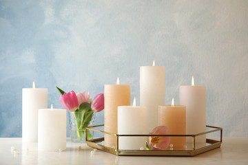 Composition with burning candles on table against color background