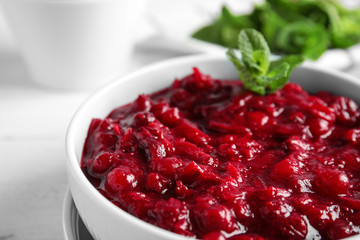 Bowl of tasty cranberry sauce with mint on table, closeup