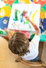 Blond child painting with colored face stained