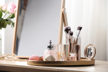 Different makeup products and accessories on dressing table in room interior - obrazy, fototapety, plakaty