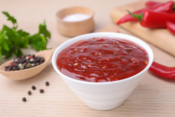Bowl of hot chili sauce and ingredients on table, closeup