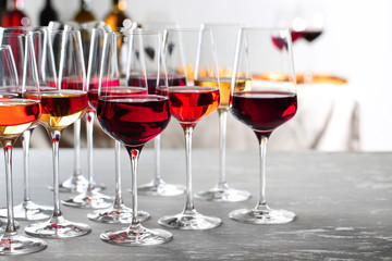 Glasses with different wines on table against blurred background. Space for text