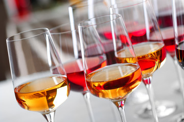 Glasses with different wines on blurred background, closeup