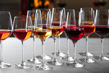Group of glasses with different wines on table against blurred background