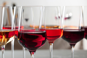 Glasses with different wines on blurred background, closeup