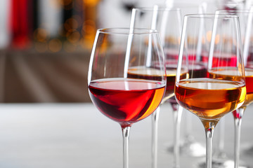 Glasses with different wines on blurred background, closeup. Space for text