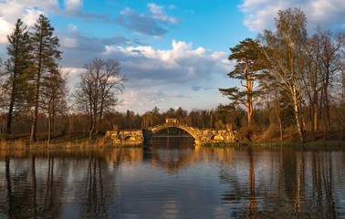 Ancient arched bridge over the lake at sunset.
