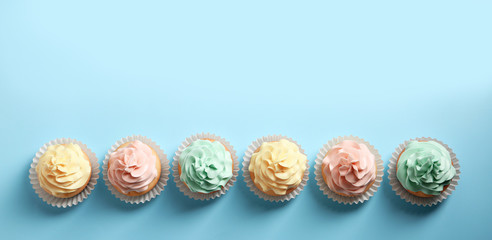 Flat lay composition with delicious cupcakes on color background, space for text