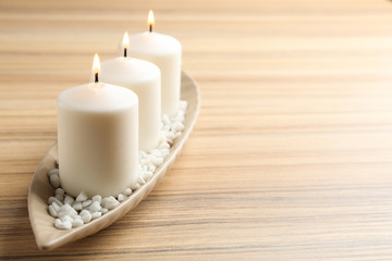 Fototapeta na wymiar Plate with three candles on wooden table. Space for text