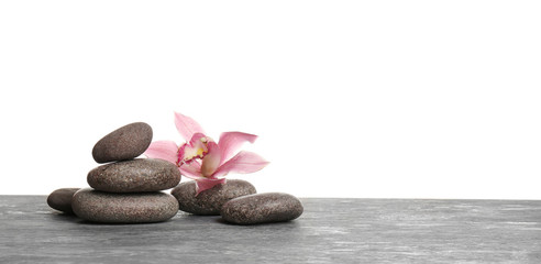 Orchid flower with spa stones on table against white background